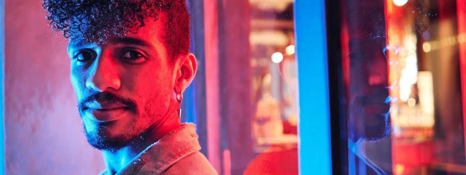 young-hispanic-man-close-to-a-neon-light-with-blue-and-red-lights-e1698314047406-qsnmrs7lz2mqkvwxwe7kig791caeox0ebf76azdi0g